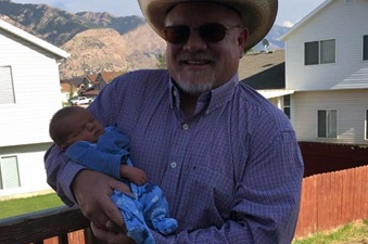 Portrait of Perry Gee holding an infant