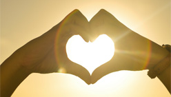 Hands forming a heart around the sun