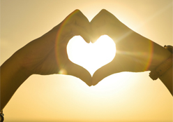 Two hand for a heart in front of a golden sunrise
