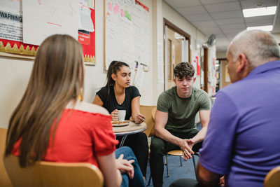 A group of young people sit in a circle in a group therapy scenario