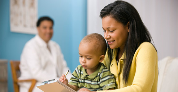 mother filling out form with son on lap