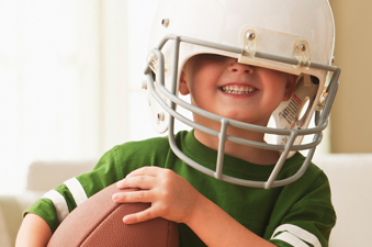little boy wearing a helmet and holding a football