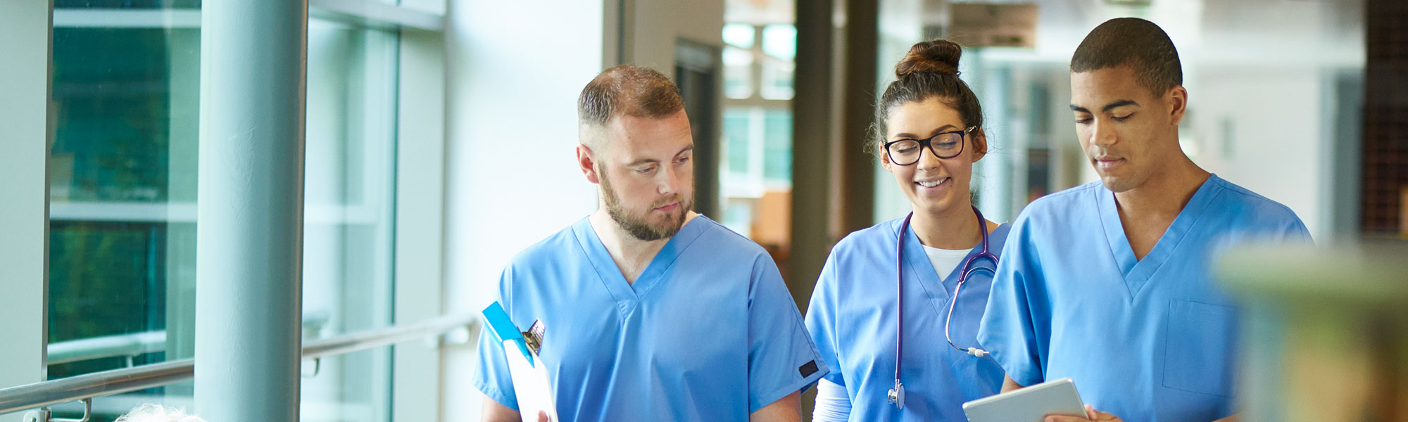 Three medical providers walking down a hallway, talking.
